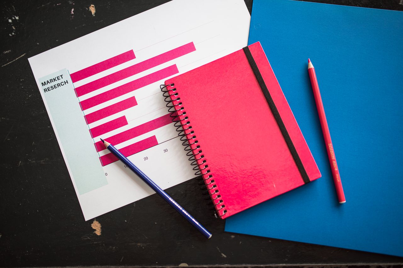 why-choose-us Vue de dessus d’un graphique d’entreprise avec un carnet rouge et des crayons de couleur sur la table.